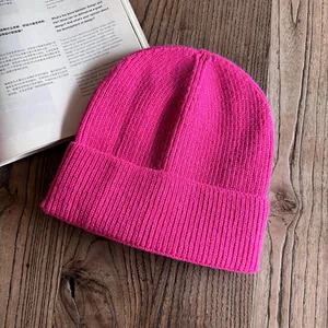 Vista piatta di un berretto in maglia a coste rosa fenicottero su sfondo in legno scuro
