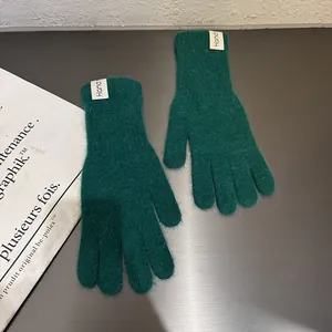 Details von dunkelgrünen Strickhandschuhen mit weichem Kunstfell und handgefertigtem Etikett