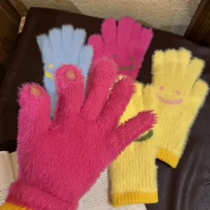 Détail de gants en peluche tricotés avec motif sourire et design sans doigts
