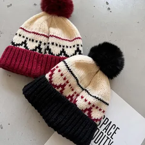 Detail van jacquard gebreide mutsen met faux fur pom-poms en golfpatronen