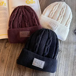 Thick cable knit beanies in burgundy, beige and black with stylish logo patches