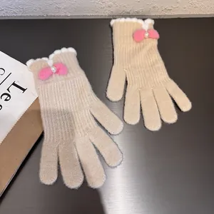 Dettaglio di guanti in maglia con fiocco rosa felpato, perla e bordi ondulati bianchi