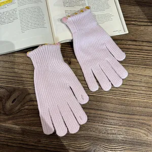 Close-up of pink knit gloves with decorative scalloped edges on a rustic book