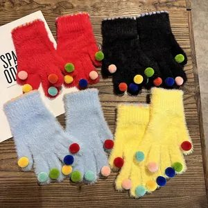 Winter-Plüschhandschuhe mit bunten Bommeln und Regenbogenstreifen auf Holzhintergrund