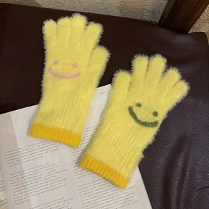 Détail de gants en peluche jaunes avec sourires tricotés sur un fond de journal vintage