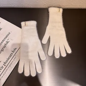 Nahaufnahme cremefarbener Strickhandschuhe mit weichem Kaninchenfell-Effekt und Etikett