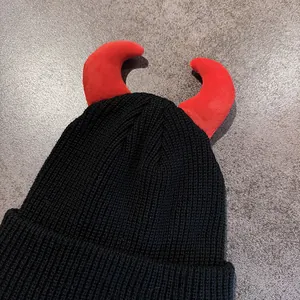 Berretto in maglia a coste nero con corna da diavolo rosse su pietra grigia