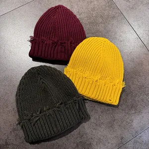 Close-up of distressed knit beanies showing ribbed texture and frayed edge details