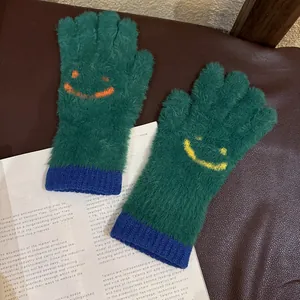 Détail de gants en peluche tricotés avec fourrure verte et motif smiley jaune brodé