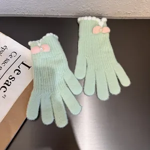 Dettaglio guanti in maglia verde menta con polsini in pelliccia, fiocchi rosa e perle