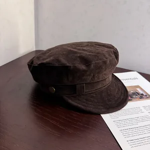Detailed shot of dark brown faux suede newsboy cap featuring decorative side metal buckle