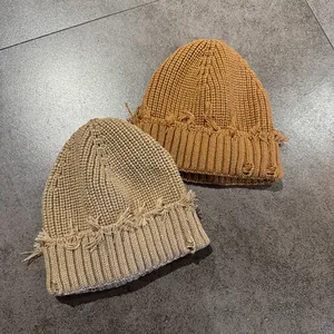 Detail of ripped knit beanies in khaki and camel with distressed fringe edges
