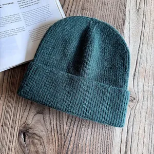 Dettaglio della texture a maglia a coste verde scuro e dell'ampio risvolto del berretto