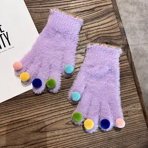 Detail von lila Plüschhandschuhen mit bunten Pompons an den Spitzen und gestreiftem Bund