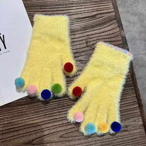 Nahaufnahme der hellgelben Plüschhandschuhe mit bunten Bommeln an den Fingerspitzen