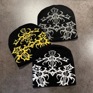 Close-up of three knitted beanies featuring gothic cross patterns in various colors