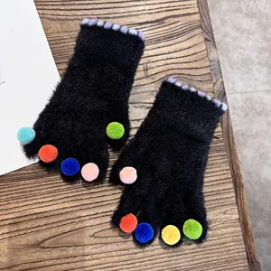 Detailansicht der flauschigen fingerlosen Handschuhe mit bunten Bommeln und Plüsch