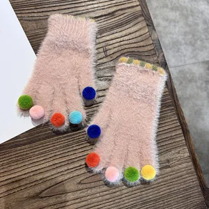 Detail von rosa Plüschhandschuhen mit bunten Bommeln an den Fingern und Streifenbündchen