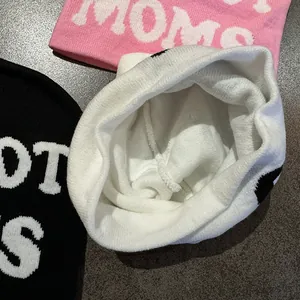 Detailed close-up of thick jacquard knit winter beanies with bold white letter patterns