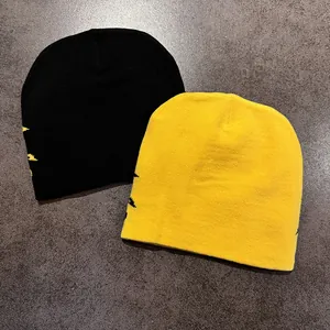 Detail of jacquard ethnic pattern on black and yellow knit beanies flat lay view