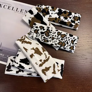 Macro detail of assorted cow print knitted headbands on a vintage wooden surface