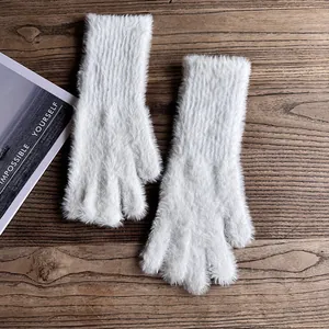 Nahaufnahme weißer Plüschhandschuhe mit langem Kunstpelz auf einer Vintage Holzoberfläche