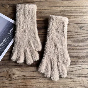 Nahaufnahme der flauschigen beige Plüsch-Winterhandschuhe auf einem rustikalen Holztisch