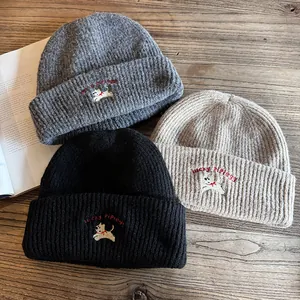 Dettaglio di berretti in maglia ricamati in nero e beige con simpatici motivi di cani