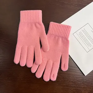 Nahaufnahme von rosa Strickhandschuhen mit gemütlichen Rippbündchen auf Holzuntergrund
