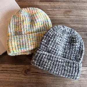 Detailed knit texture of thick beanies in candy mix and grey colors on wood surface