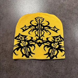 Close-up of yellow knit beanie with black gothic cross and ethnic jacquard patterns