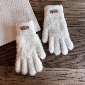 Detail von weißen Plüsch-Strickhandschuhen mit Rentier-Patch und Schneeflocken
