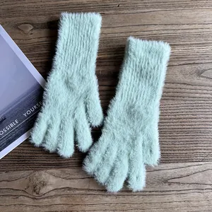 Detail von hellgrünen Webpelz-Handschuhen mit Rippbündchen auf dunklem Holz