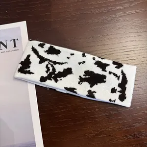 Detail view of the black and white cow print knitted sports headband on wood background