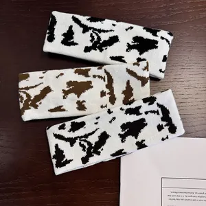 Three-piece knitted headbands set featuring cow and leopard prints on dark wood