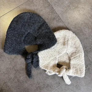 Close-up of thick bouclé fleece ear-protection hats in dark grey and beige with chin straps