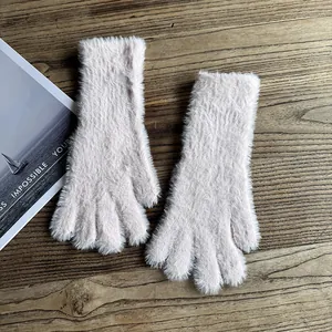Nahaufnahme weicher rosa Pelzhandschuhe auf Holztisch mit dekorativem Magazin im Hintergrund