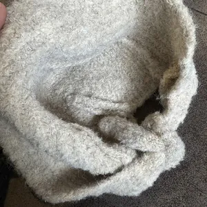 Detailed texture of beige bouclé knit balaclava hat with warm fluffy finish