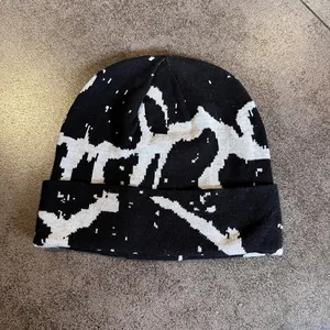 Detail view of the black and white abstract graffiti jacquard pattern on a knit beanie