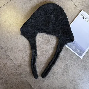 Flat lay of a thick black fleece Balaclava hat with ties on a marble surface