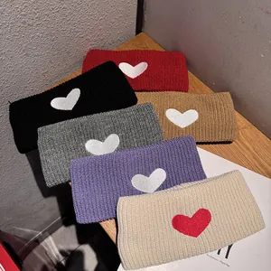 Close-up of six color knitted headbands with heart embroidery on textured wood surface
