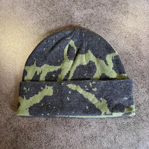 Detailed knit texture of dark grey beanie with neon green abstract pattern