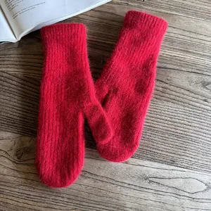 Detailed macro view of vibrant red faux rabbit fur mittens on a rustic wooden desk