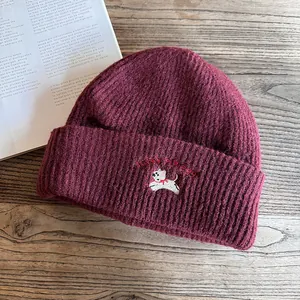 Dettaglio del berretto in maglia bordeaux con ricamo di cucciolo e scritta Lucky ricamata