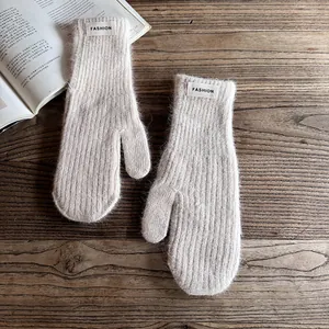 Close-up of beige knit mittens with fuzzy mohair texture and Fashion fabric label