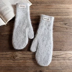 Close-up of grey plush mittens with Fashion label on a rustic wooden background