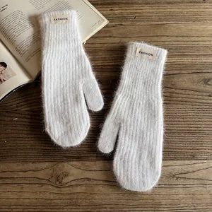 Detailed macro of white plush mittens with a FASHION label on rustic wood