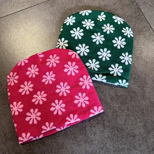 Detailed knit texture of colorful floral jacquard beanies in pink and dark green colors
