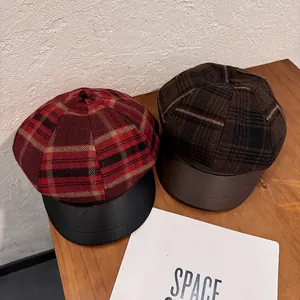 Vintage red plaid newsboy cap with leather brim for women shown on wooden background