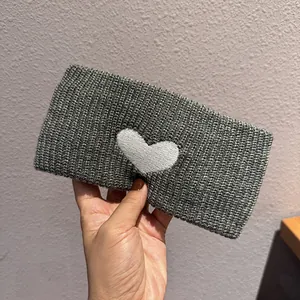 Detail showing grey knitted headband with white heart embroidery and soft texture